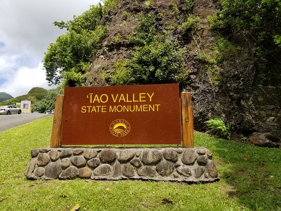 The Iao Needle rises above a stream and lush tropical vegetation on the island of Maui, Hawaii.